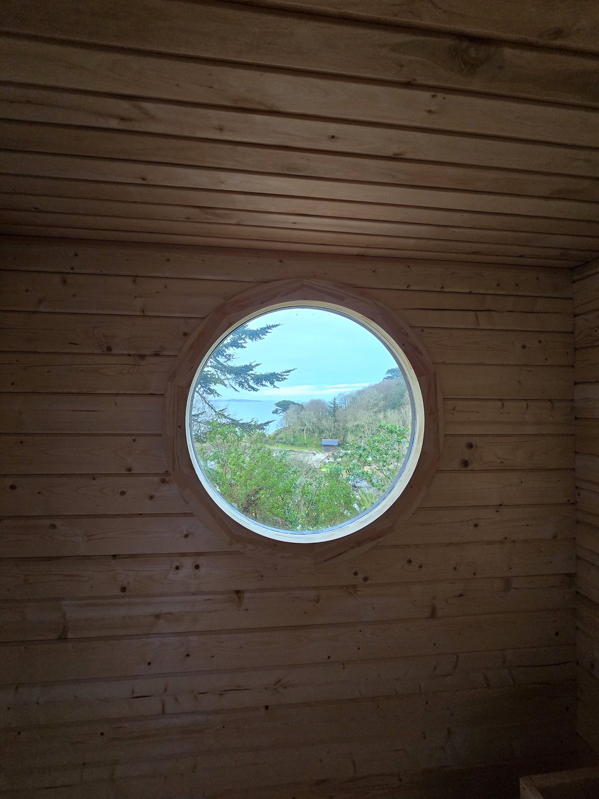 View across the cove and out to sea through the sauna's circular window